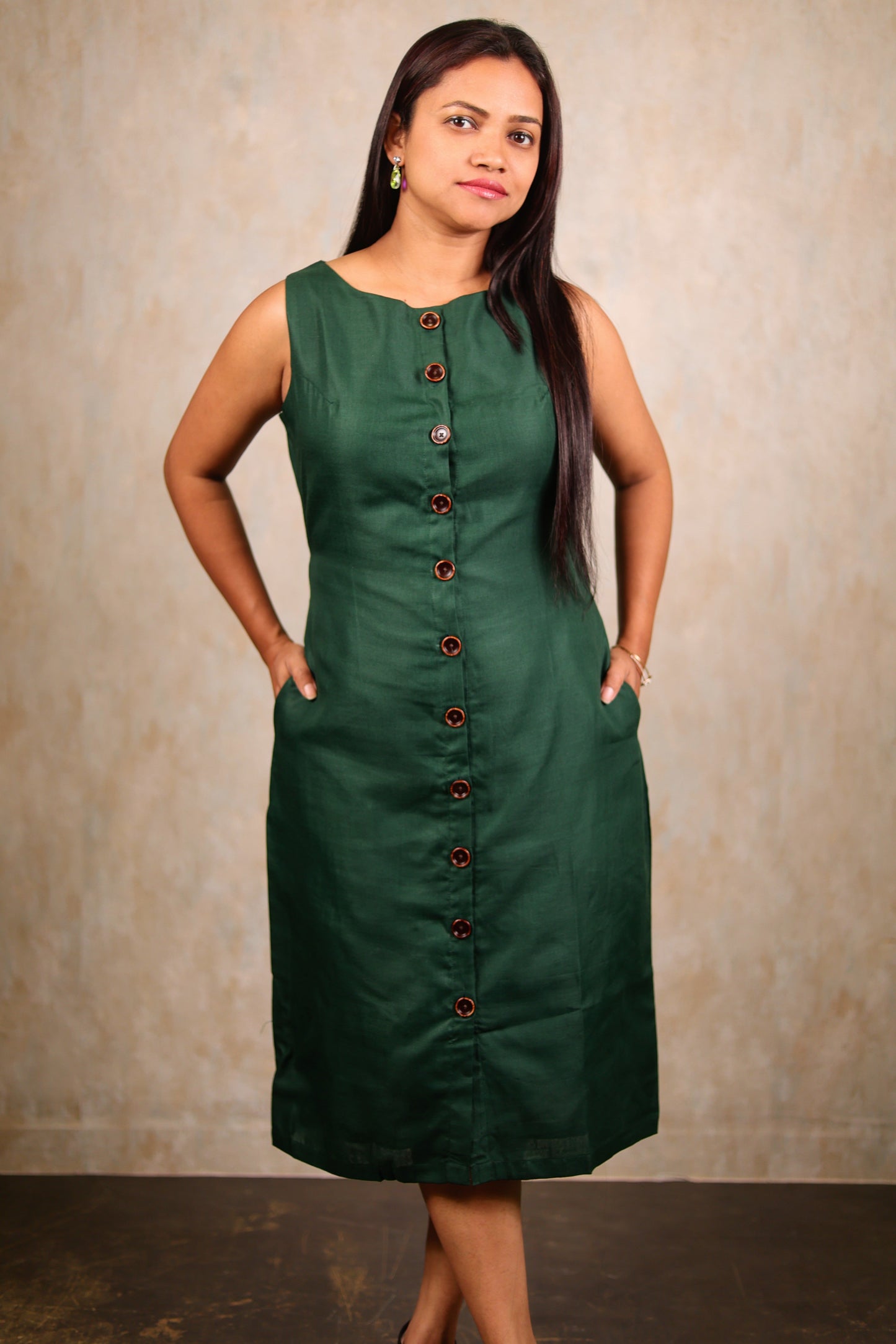 Close up of a woman wearing a cotton green midi dress with her hands in the pockets