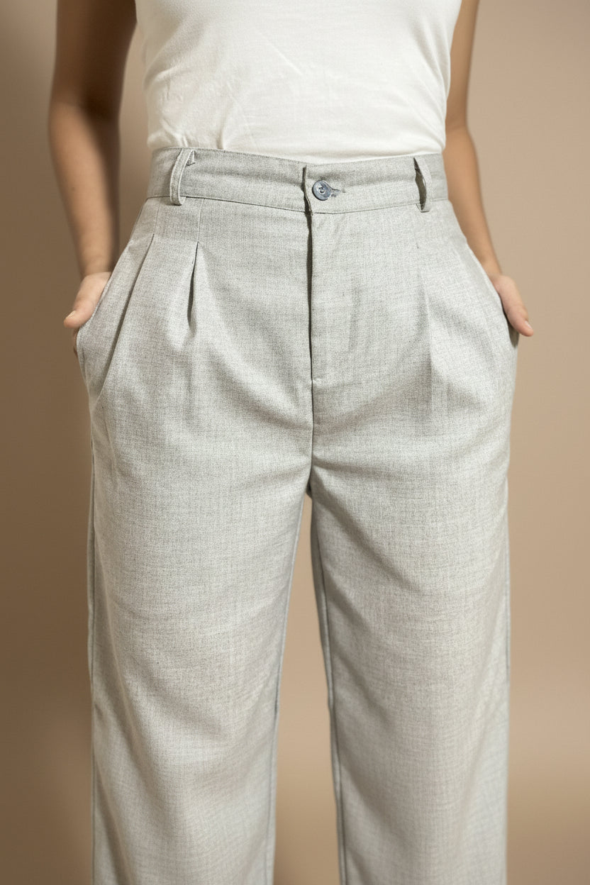 Light gray pleated petite pants worn by a woman with her hands in pockets