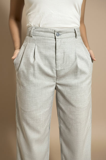 Light gray pleated petite pants worn by a woman with her hands in pockets